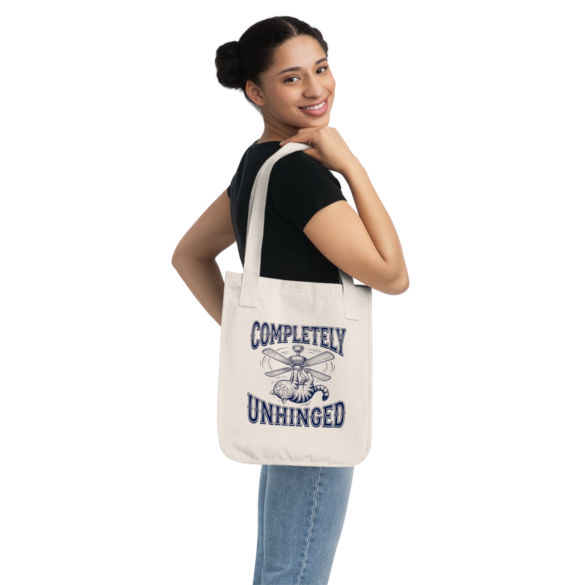 Woman holding a tote bag with 'Completely Unhinged' text and graphic on a white background
