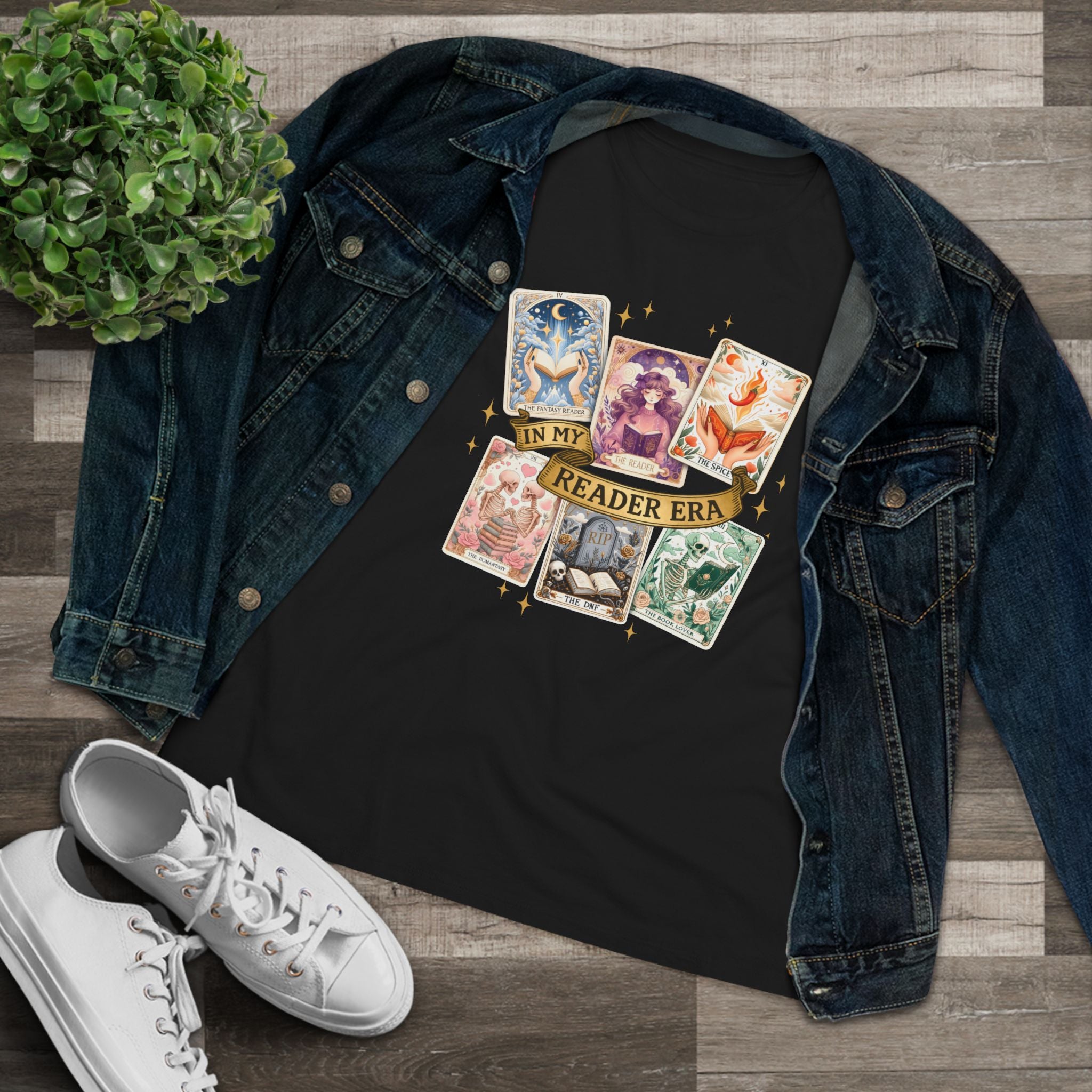 Black t-shirt with tarot card designs and 'Reader Era' text, paired with a denim jacket and white sneakers on a wooden surface.