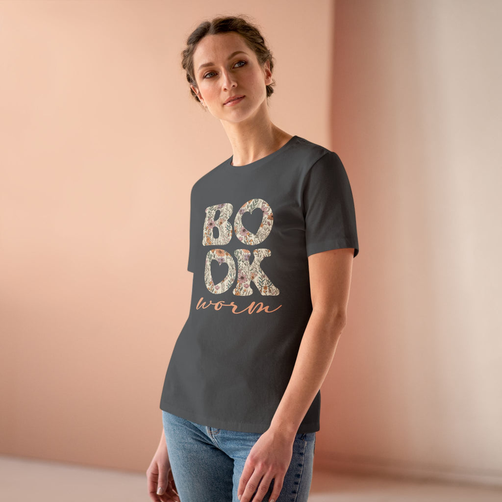 Woman wearing a dark gray t-shirt with 'BOOKworm' text on a peach background