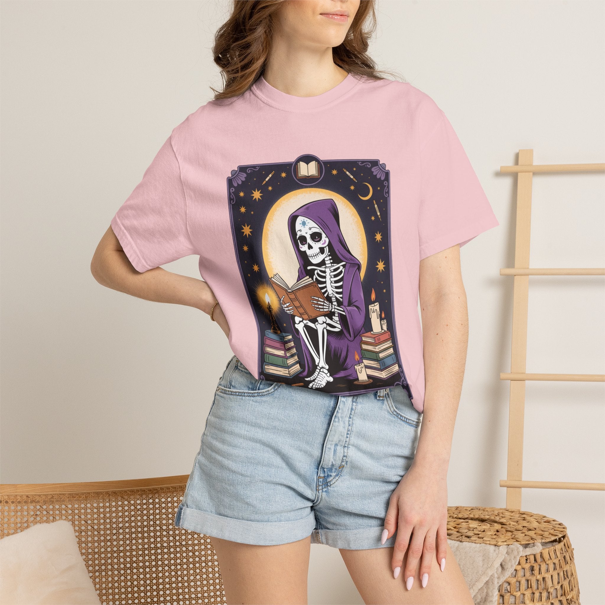 Person wearing a pink t-shirt with a graphic design of a skeleton and books.